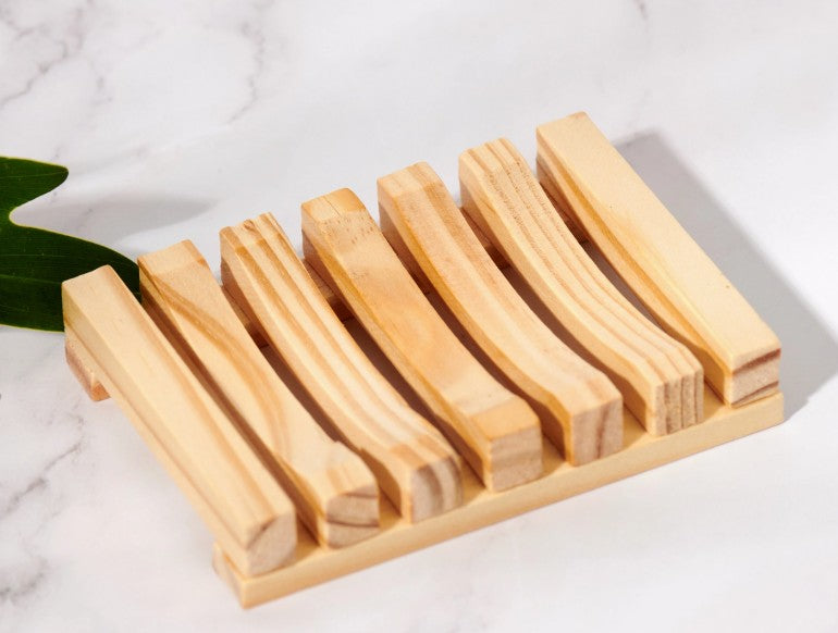 Light wooden soap dish with slotted design on a marble surface