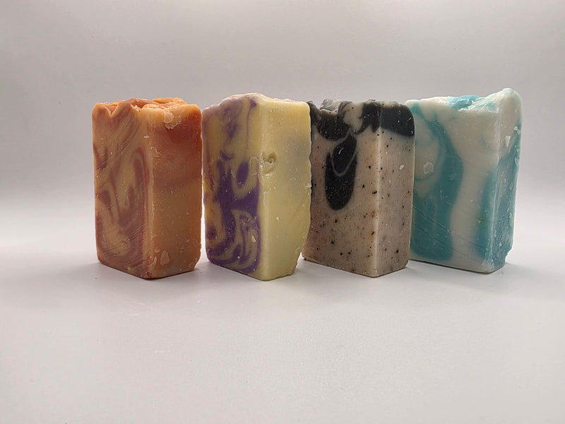 Four different colored soap bars on a light gray background